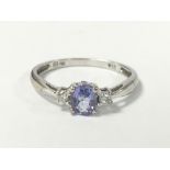 A LADIES 9CT WHITE GOLD RING WITH CENTRAL CLAW SET TANZANITE FLANKED BY TWO SINGLE DIAMONDS, RING