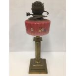 A BRASS COLUMN OIL LAMP WITH RED AND WHITE OPAQUE GLASS OIL RESERVOIR, 48CM HIGH