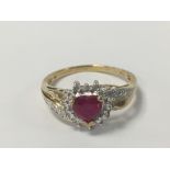 A 9CT GOLD LADIES RING WITH CENTRAL CLAW SET HEART SHAPED RUBY SURROUNDED BY ILLUSION SET