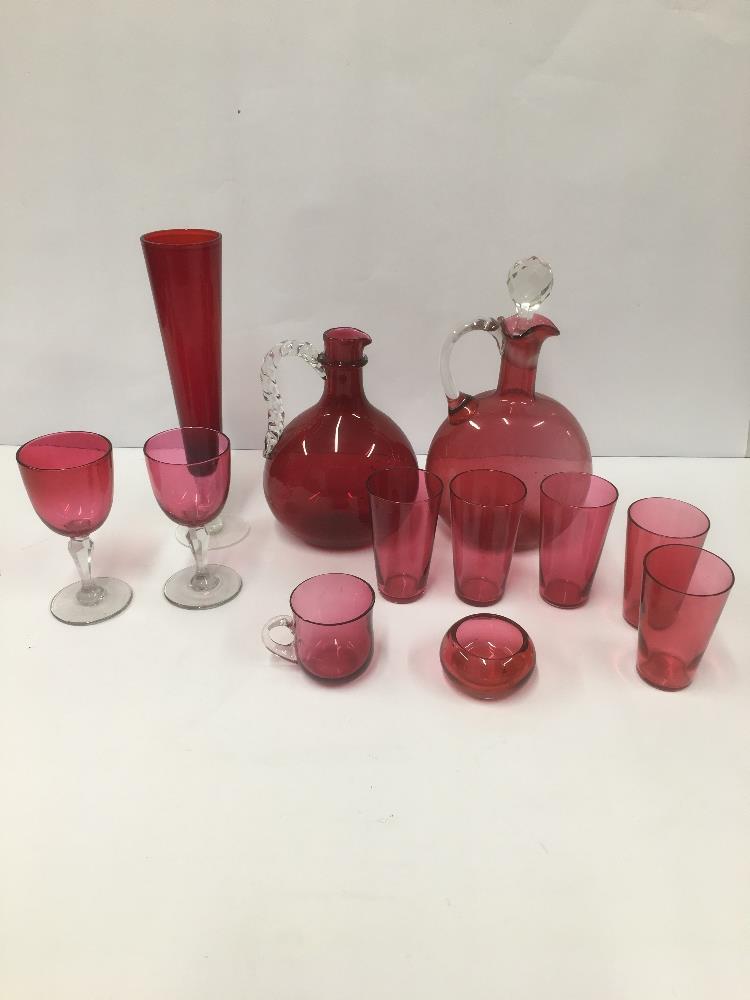 A GROUP OF CRANBERRY GLASS ITEMS, INCLUDING TWO DECANTERS AND DRINKING GLASSES, LARGEST 25.5CM HIGH