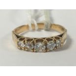 AN UNMARKED 18CT GOLD AND DIAMOND RING, THE CENTRAL CLAW SET STONE FLANKED BY FOUR MORE OF
