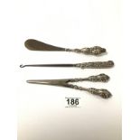 A SILVER HANDLED EMBOSSED PAIR OF GLOVE STRETCHERS, TOGETHER WITH A SIMILAR SHOE HORN AND BUTTON