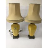 A PAIR OF YELLOW CERAMIC TABLE LAMPS WITH BRASS BASES