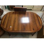 AN EXTENDING ROSEWOOD DINING TABLE WITH ADDITIONAL LEAF.