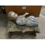 A FRENCH RELIGIOUS PLASTER FIGURE OF BABY JESUS IN A MANGER, 36CM WIDE (AF)