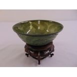 A Chinese spinach jade bowl carved in low relief with dragons chasing a flaming pearl, on carved