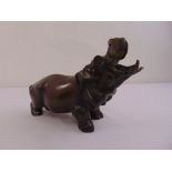 A bronze figurine of a hippopotamus with mouth agape