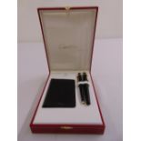 A Cartier cased set of matching pens and a card holder