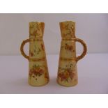A pair of Royal Worcester blush ivory jugs painted with flowers and gilded decorations
