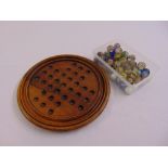 A Victorian circular wooden solitaire board with accompanying marbles