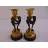 A pair of gilt metal and brass table candlesticks, formed as three mythical birds supporting vase