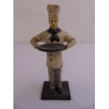 A calling card dispenser in the form of a painted cast iron chef holding a platter on rectangular