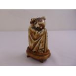 An oriental carved horn figurine of a seated gentleman, signed to the base