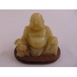 A Chinese jadeite carved figurine of Buddha on oval wooden plinth