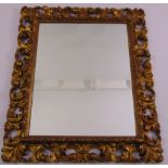 A rectangular pierced and carved gilded wooden wall mirror, 90 x 75cm