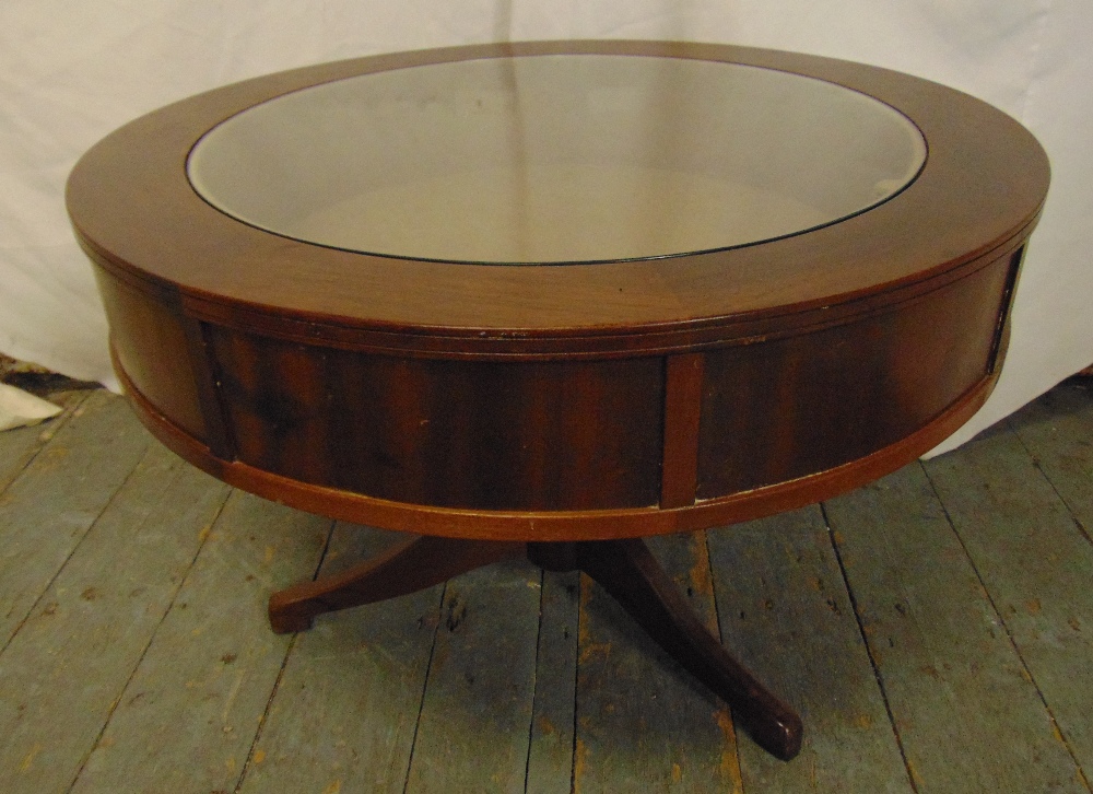 A mahogany circular coffee table with glass display case to the centre on three outswept legs