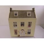 A cream painted double storey dolls house, the hinged front revealing a quantity of dolls house