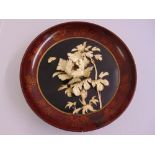 An oriental wall relief with bone flowers and leaves within a circular lacquered frame