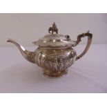 An Indian white metal teapot chased to the sides with figures in landscapes the raised hinged