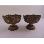 A pair of Far Eastern white metal circular bowls profusely chased with stylised figures and