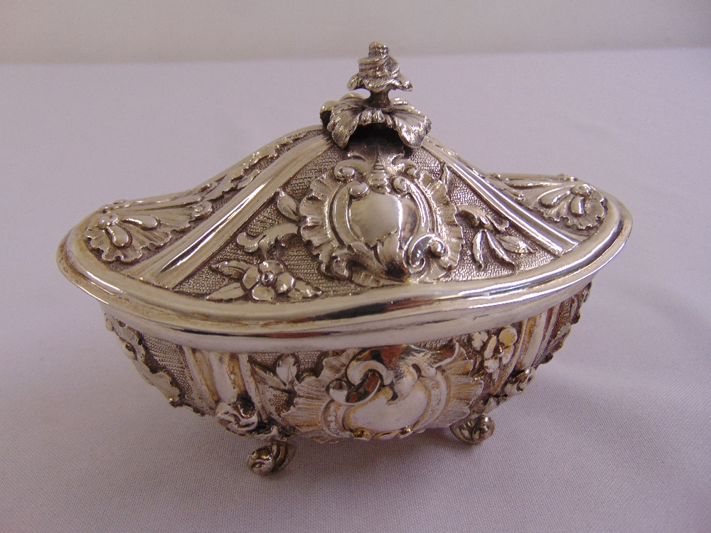 A continental white metal shaped oval box and cover leaf and scroll chased sides on leaf scroll