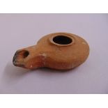 A Roman terracotta oil lamp of customary form