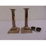 A pair of silver table candlesticks of panelled cylindrical form on raised square bases with