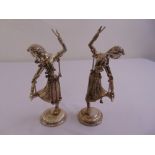 A pair of Far Eastern white metal dancing figurines on raised circular fluted bases