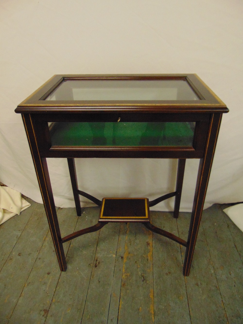 A mahogany and glass rectangular display case on four tapering rectangular legs