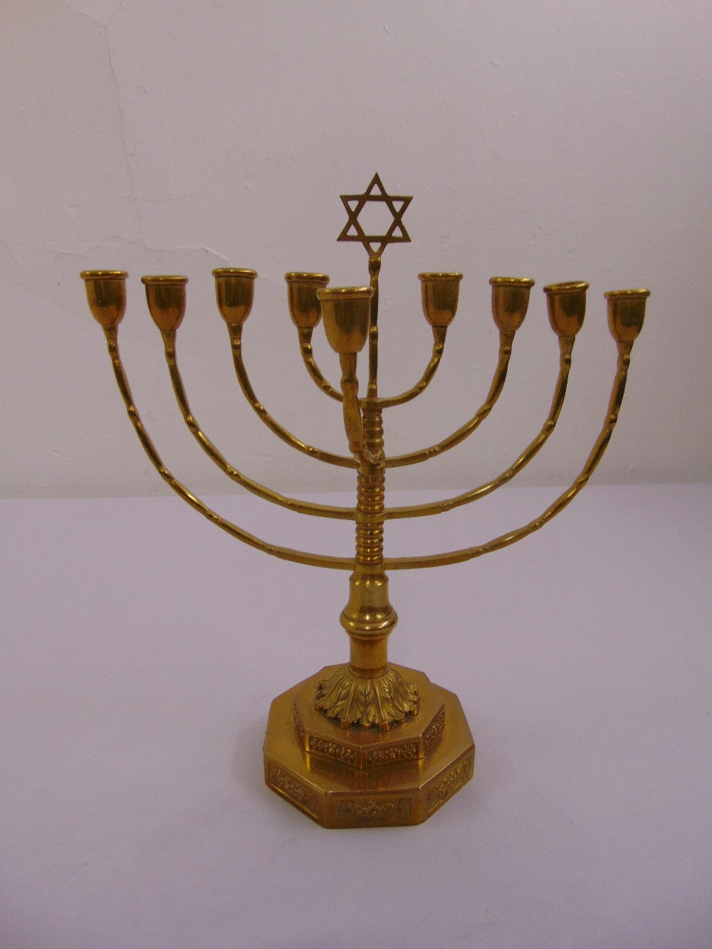 A brass Menorah of customary form on stepped octagonal base