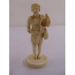 A 19th century ivory figurine of a man carrying a bag and oil lamp on raised circular base