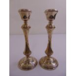 A pair of silver filled table candlesticks of waisted cylindrical form on raised circular bases,