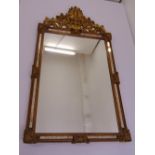 A decorative rectangular gilded wooden wall mirror surmounted by a pierced and carved floral design