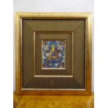 A framed Tibetan mandala watercolour of a deity on a lotus throne, 12.5 x 10cm