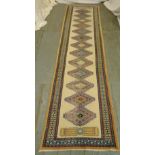 A cream ground wool runner with repeating geometric pattern and border, 303 x 78.5cm