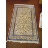 A Persian wool carpet cream ground with repeating floral pattern and blue floral border, 254 x
