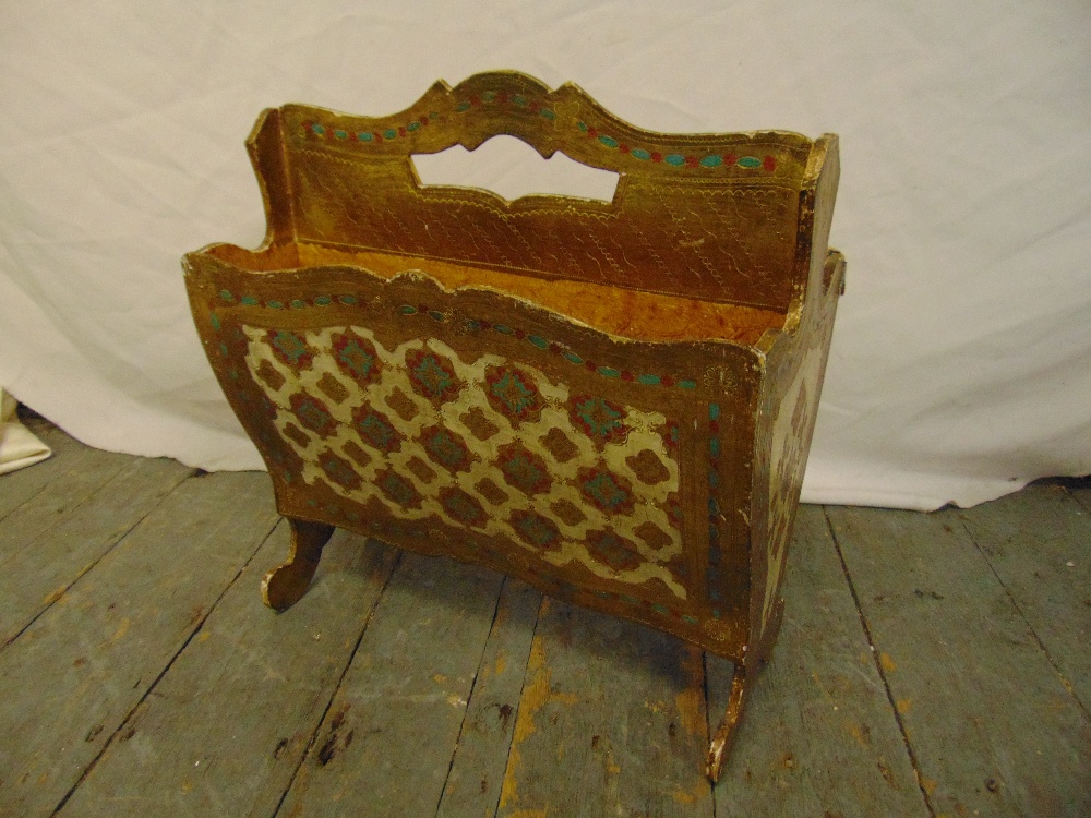 A gilded Florentine wooden magazine rack on scroll legs with pierced carrying handle