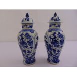 A pair of Chinese blue and white baluster vases with pull off covers decorated with flowers and