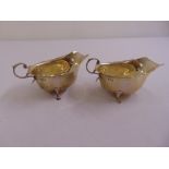 A pair of silver sauce boats, oval, cut edge with leaf capped flying scroll handles on three