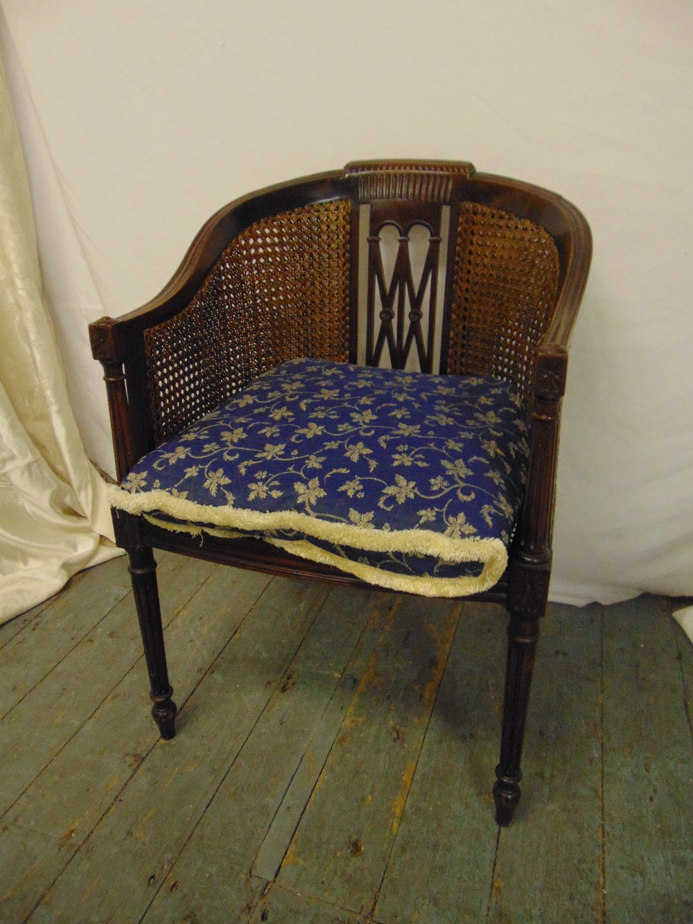 An Edwardian mahogany occasional chair with bergere seat and back on four fluted cylindrical legs