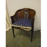 An Edwardian mahogany occasional chair with bergere seat and back on four fluted cylindrical legs