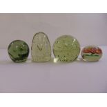 Four glass paperweights of varying shape and size