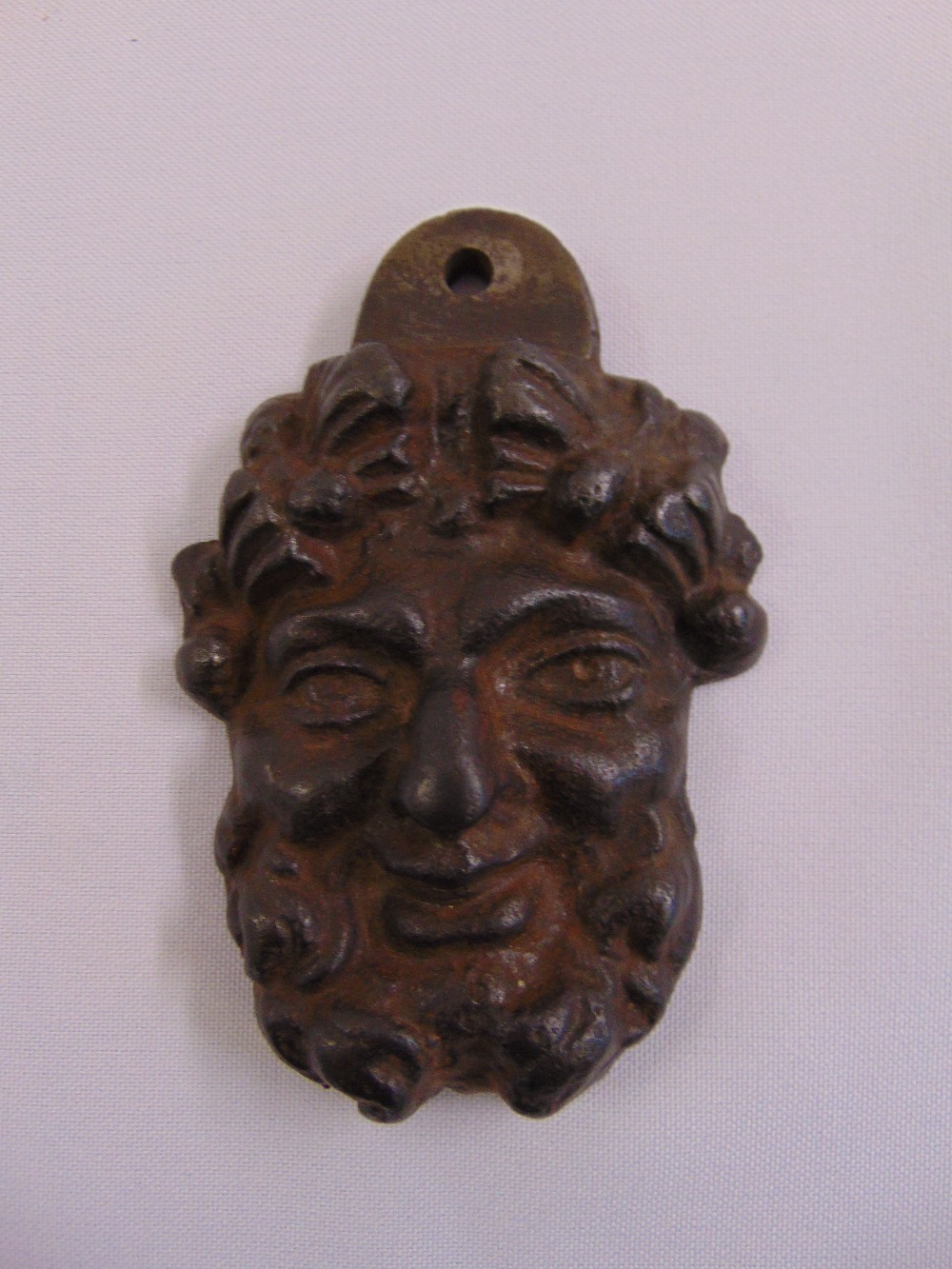 A cast bronze door knocker in the form of a mans bearded visage