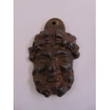 A cast bronze door knocker in the form of a mans bearded visage