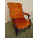 A Victorian upholstered button back mahogany armchair on scroll legs