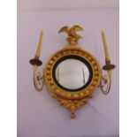An Empire style circular convex wall mirror, decorated gilded wooden frame with two candle