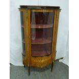 An oval Kingswood inlaid glazed display cabinet with gilt metal mounts, hinged glazed door on four