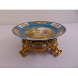 A Sevres style hand painted porcelain table centrepiece mounted on a pierced gilded metal base