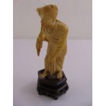 A 19th century Indian ivory figurine of a snake charmer on hardwood stand, 15cm (h)