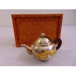 A cased Korean white metal teapot decorated with applied yellow metal dragon to the side